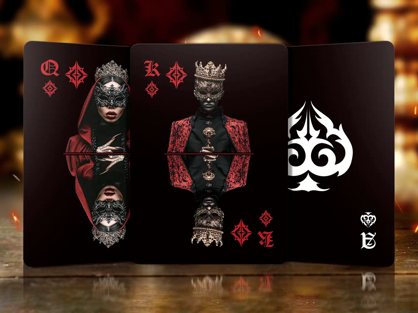 Three playing cards with artistic designs on a reflective surface.