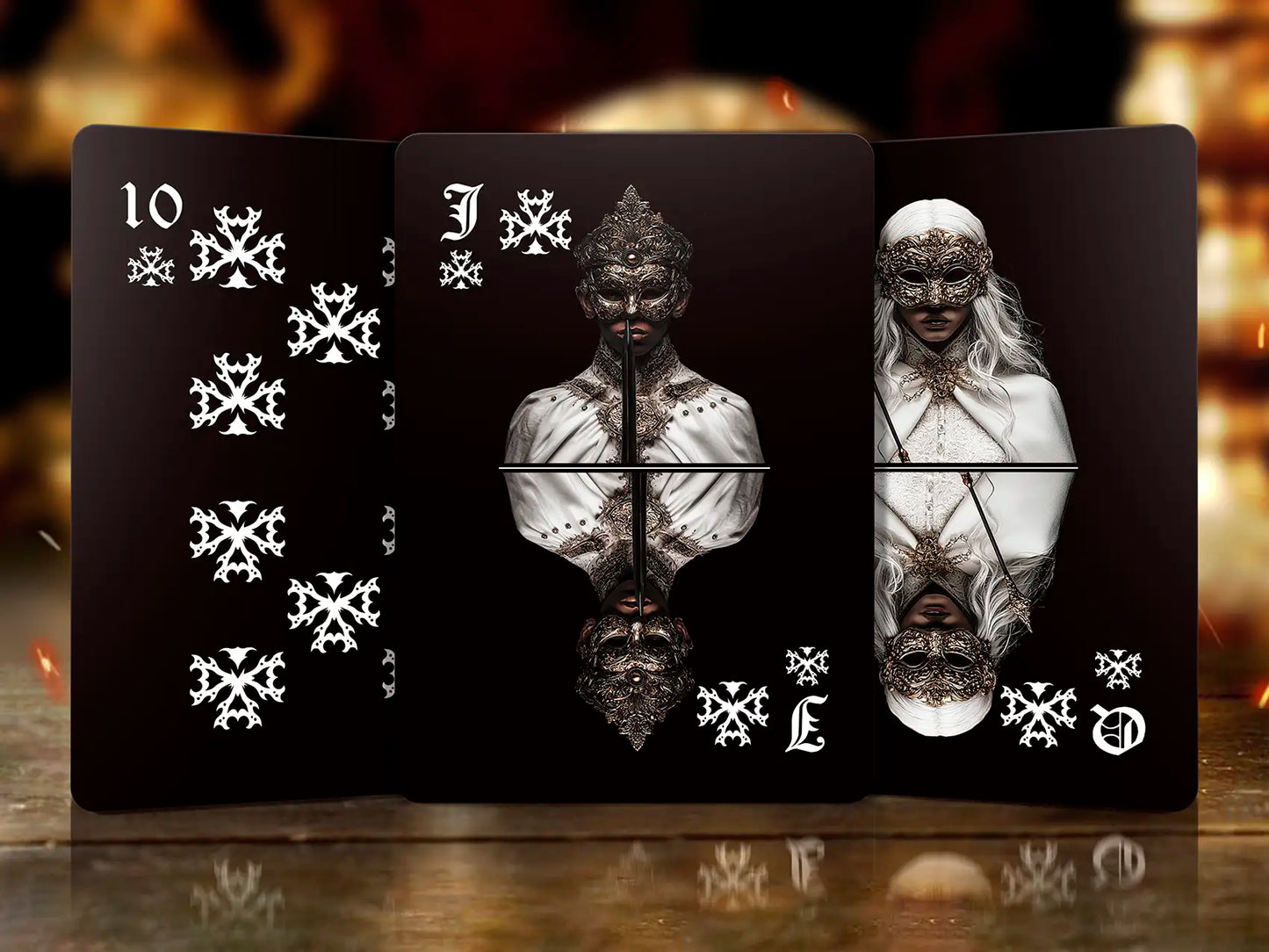 Three playing cards with black backgrounds and white designs on a reflective surface.