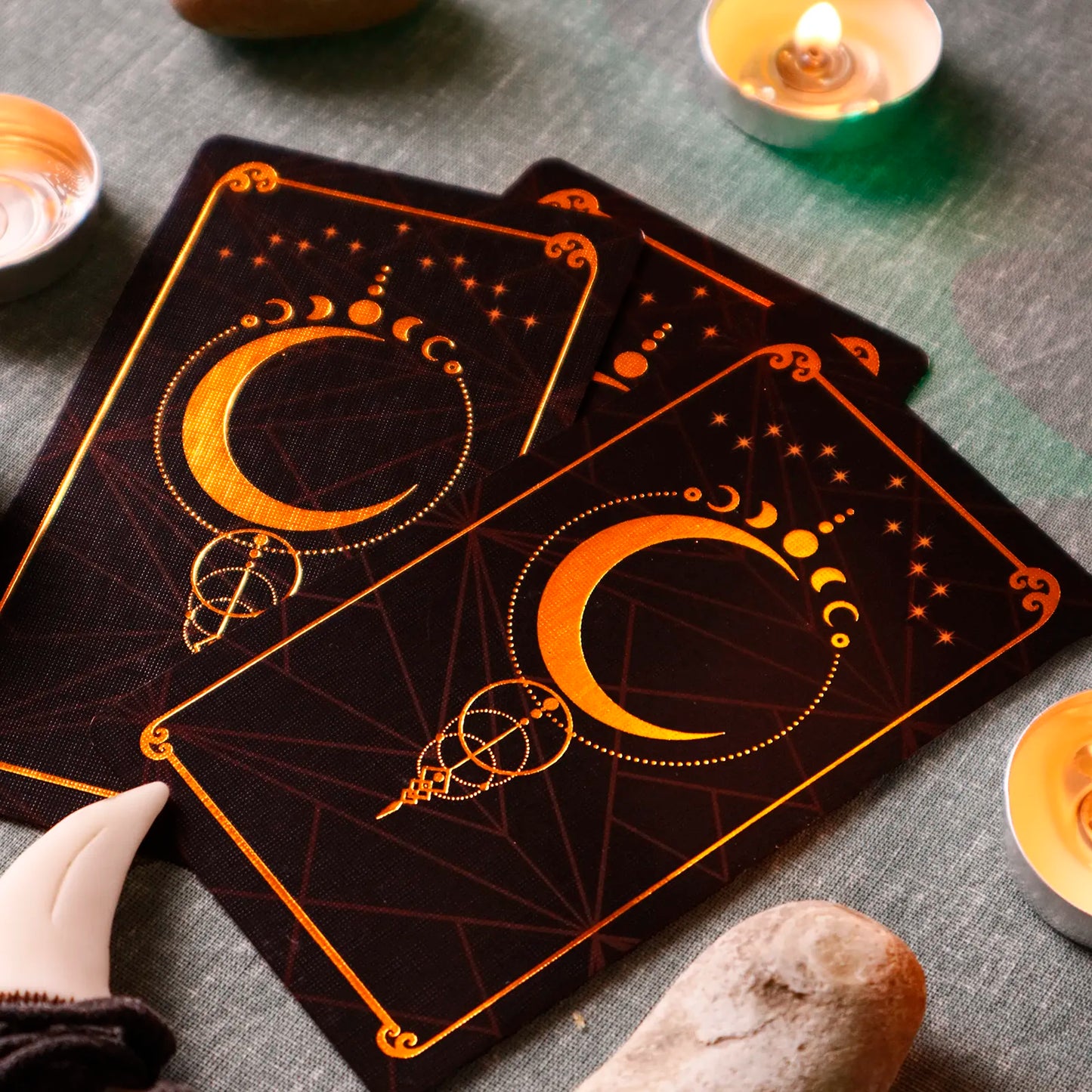 Decorative tarot cards with celestial design on a textured surface with candles and stones.