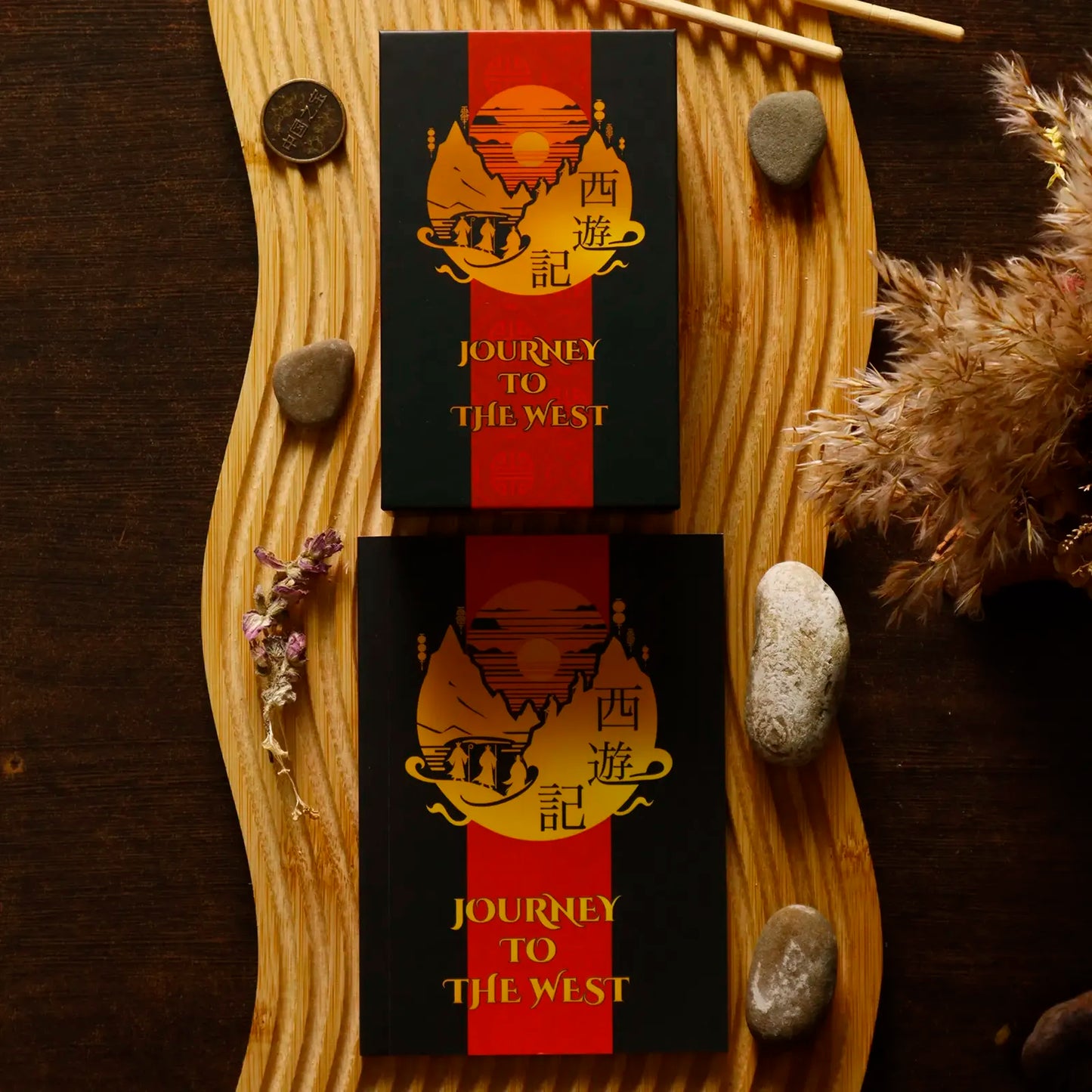 Two 'Journey to the West' books on a wooden surface with decorative elements.