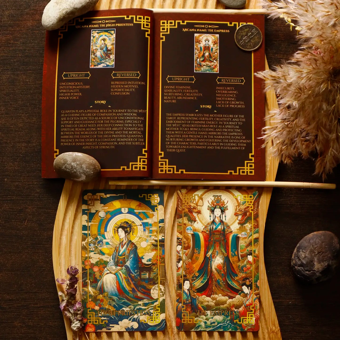 Decorative tarot guidebook with colorful illustrations and text on a wooden stand, surrounded by stones and feathers.