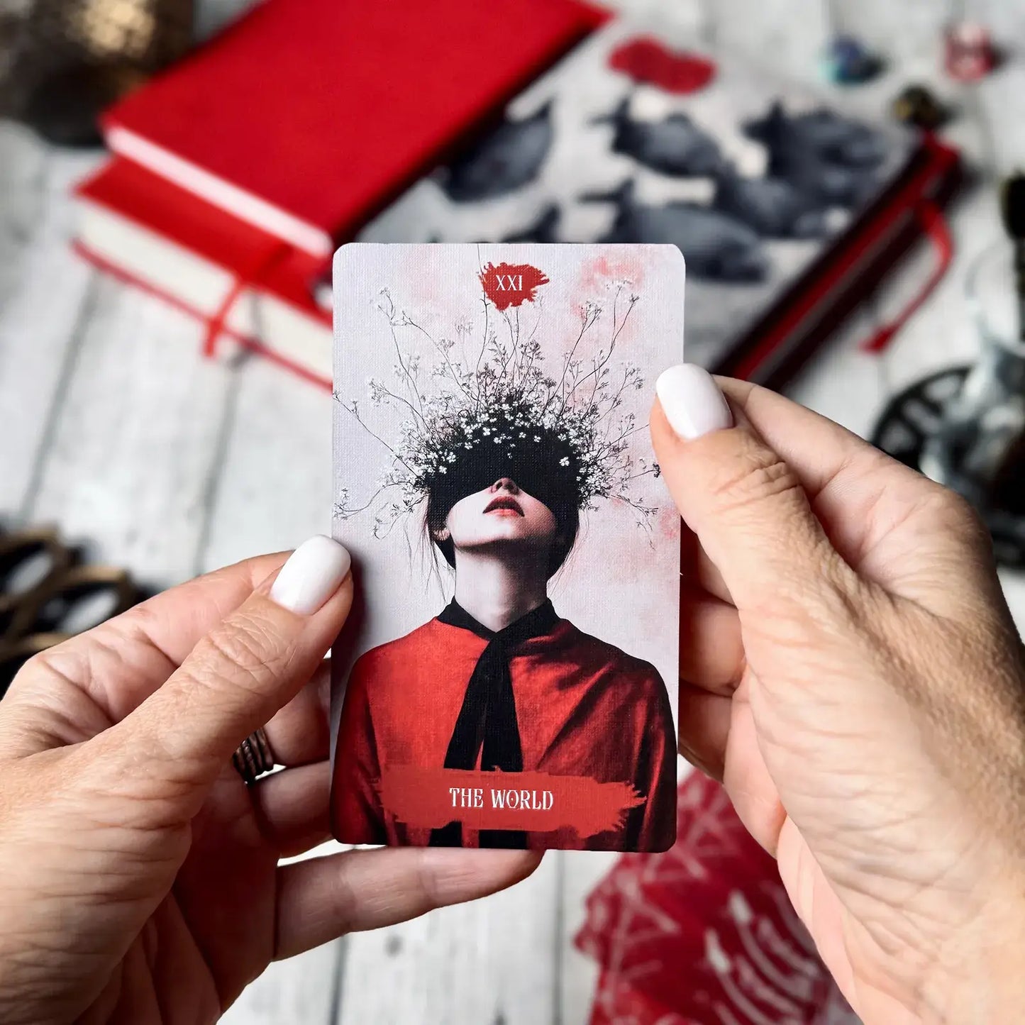 Card with a person in a red outfit and black headscarf held by hands against a blurred background.