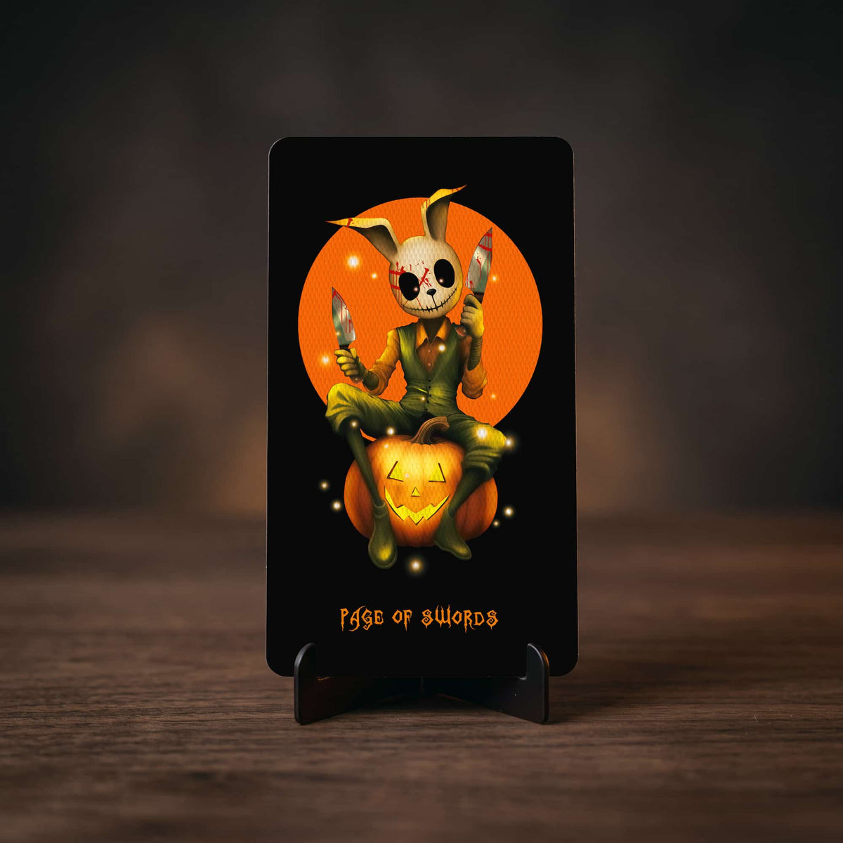 Halloween Tarot Page of Swords card, rabbit-masked figure with knives sitting on a pumpkin