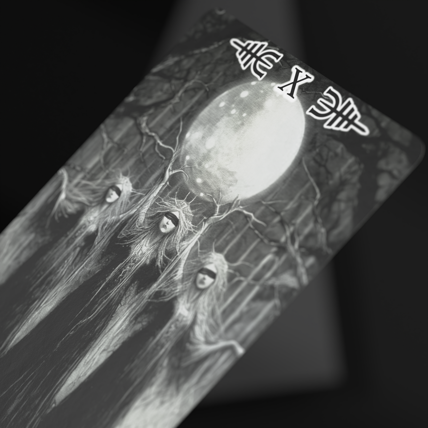 Close-up of Viking tarot card featuring three mysterious hooded women under a full moon, black and white fantasy tarot deck illustration, gothic oracle deck art for collectors and divination enthusiasts