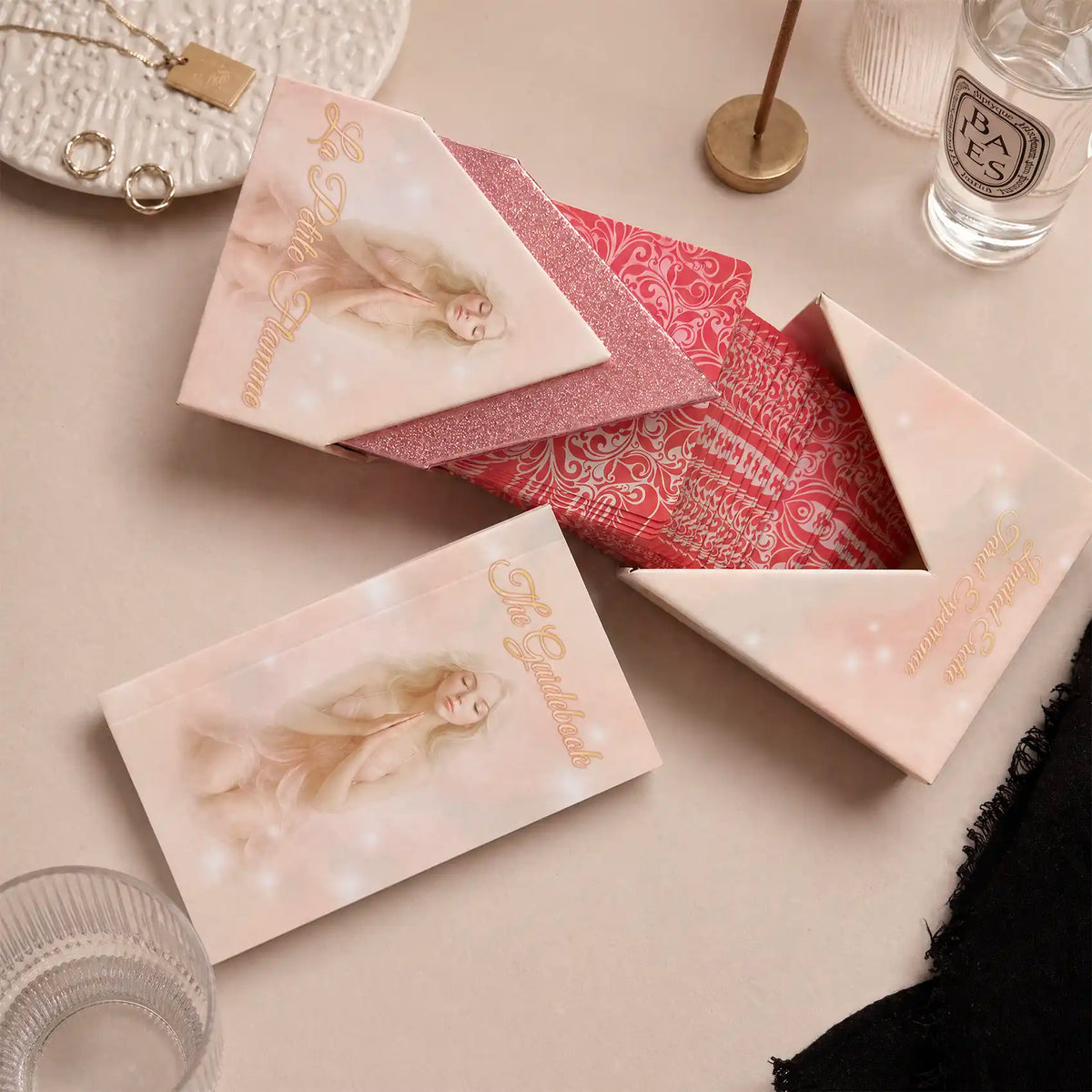 La Petite Flamme Tarot flat lay with open box, red card backs, glitter inner box and printed guidebook