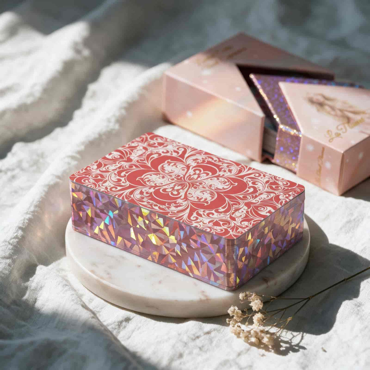 La Petite Flamme Tarot deck with red ornate card back and holographic pink gilded edges on marble tray