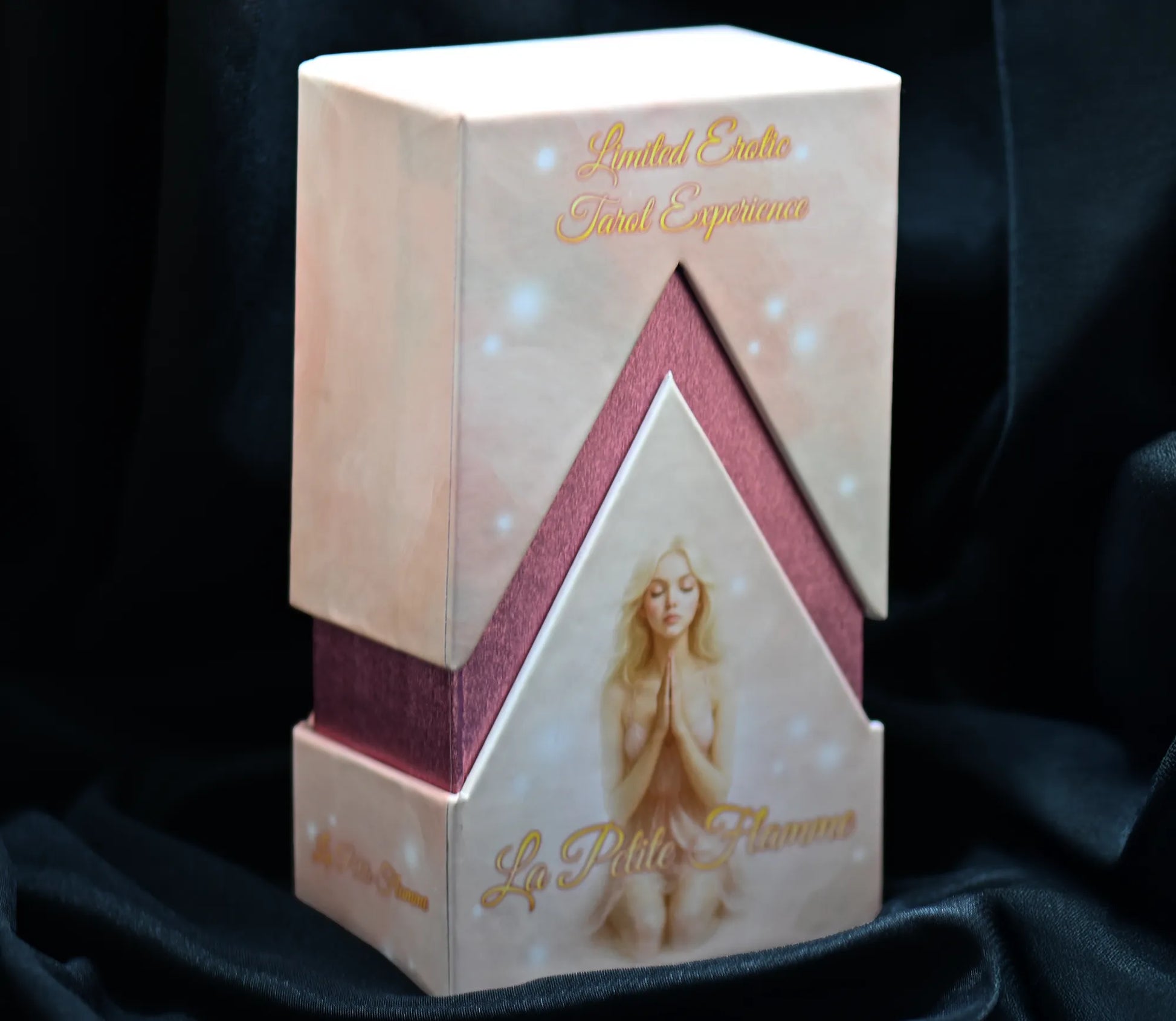 Decorative box with a woman's face and 'La Petite Flamme' branding on a dark fabric background