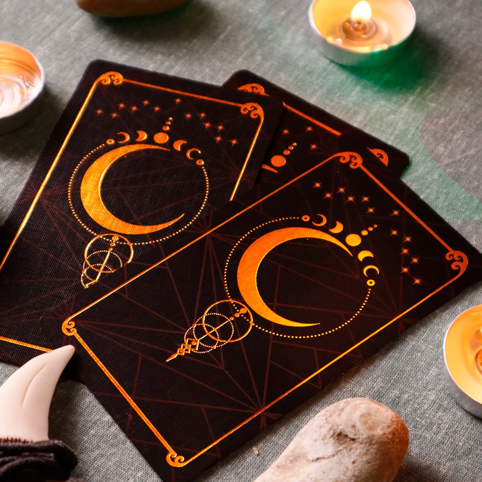 Decorative tarot cards with celestial design on a textured surface with candles and stones.