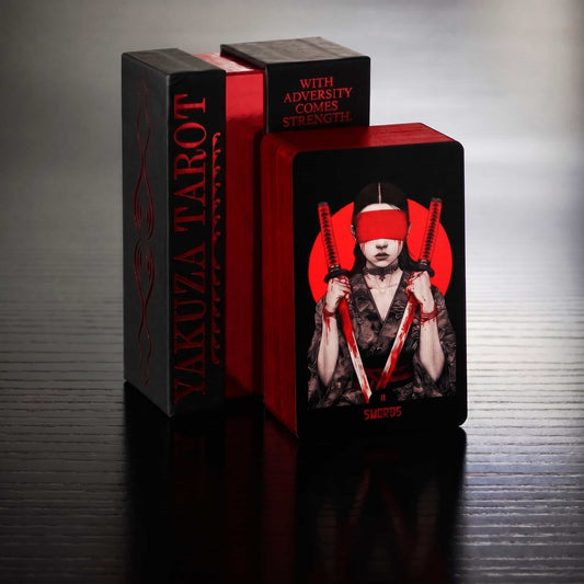 Yakuza Tarot card box and card with person holding two swords on a reflective surface. Card two of swords 