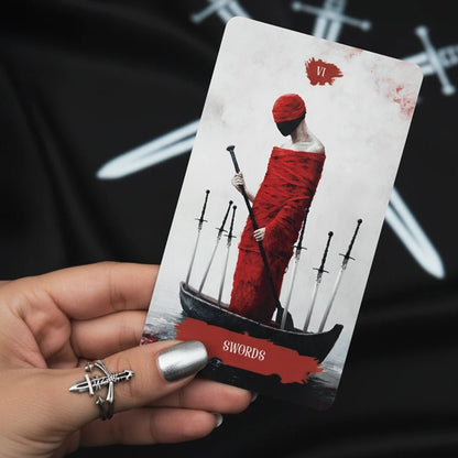 Arcana Obscura Six of Swords tarot card held in hand with red cloaked figure and swords composition