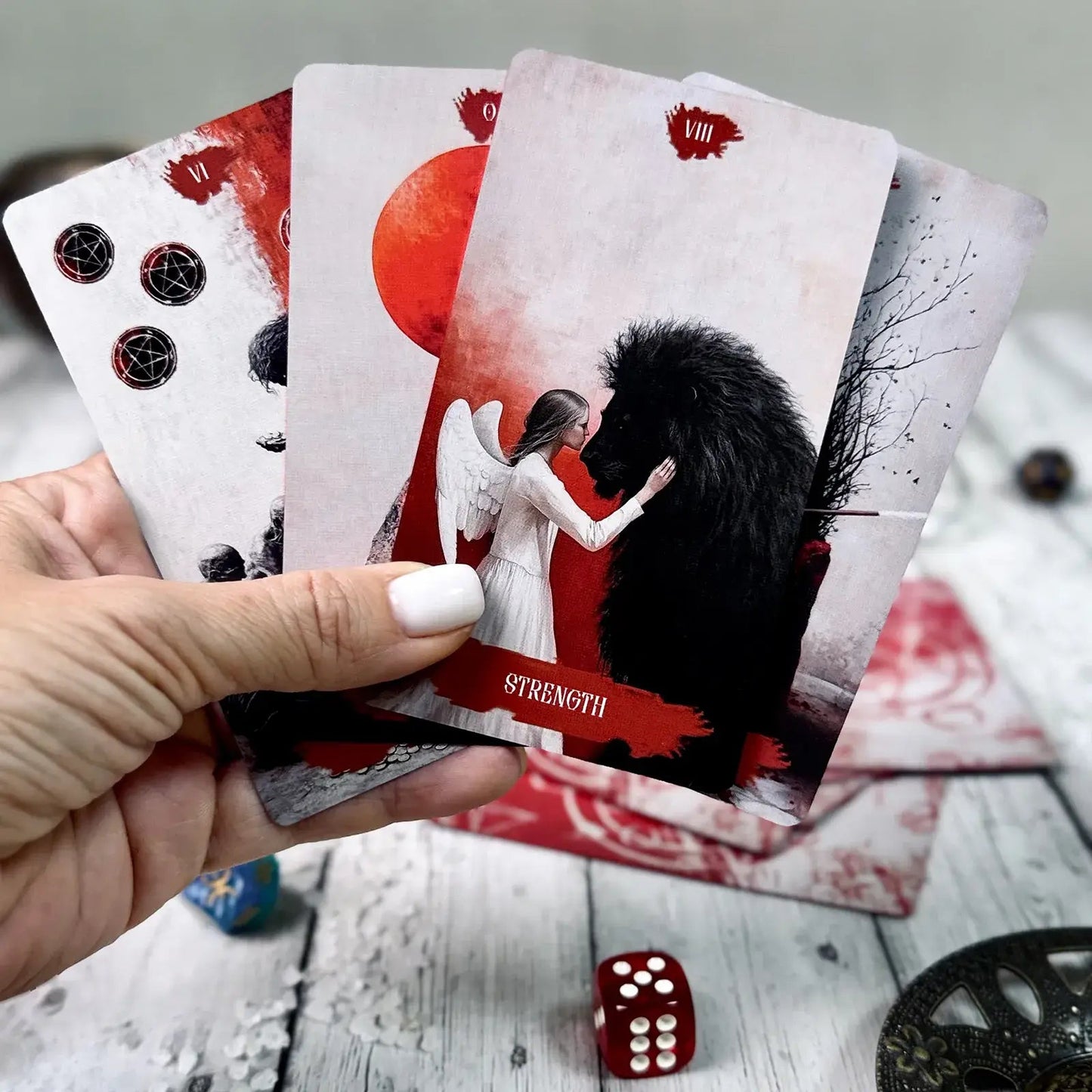 Arcana Obscura Strength tarot card held in hand with lion and angel illustration red black aesthetic