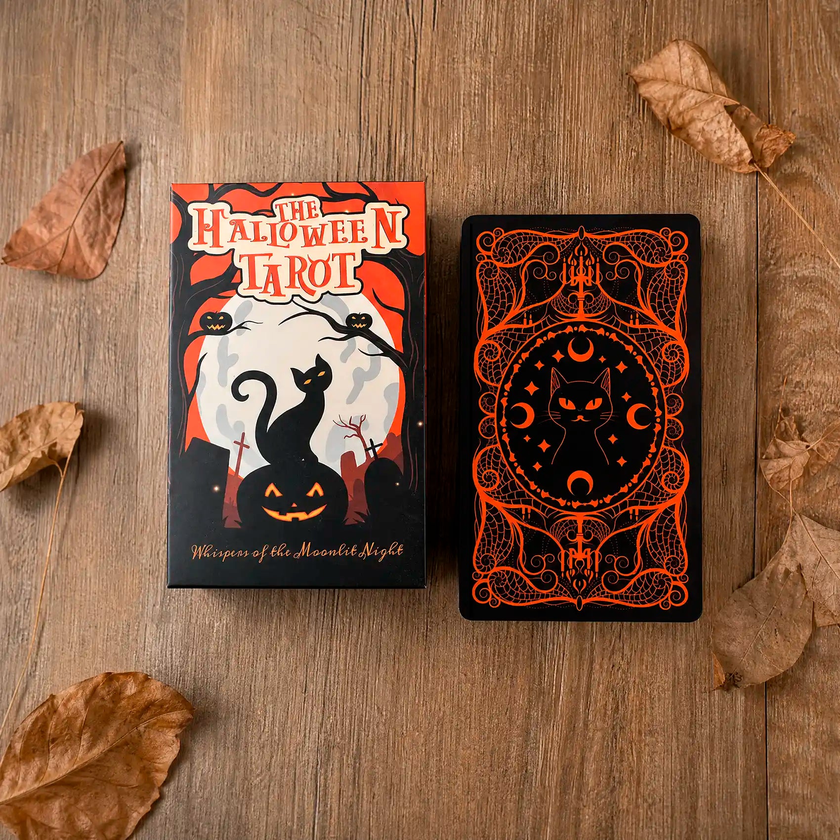 Halloween Tarot collector box and card back displayed on wooden table with pumpkin orange artwork, black cat design and autumn leaves