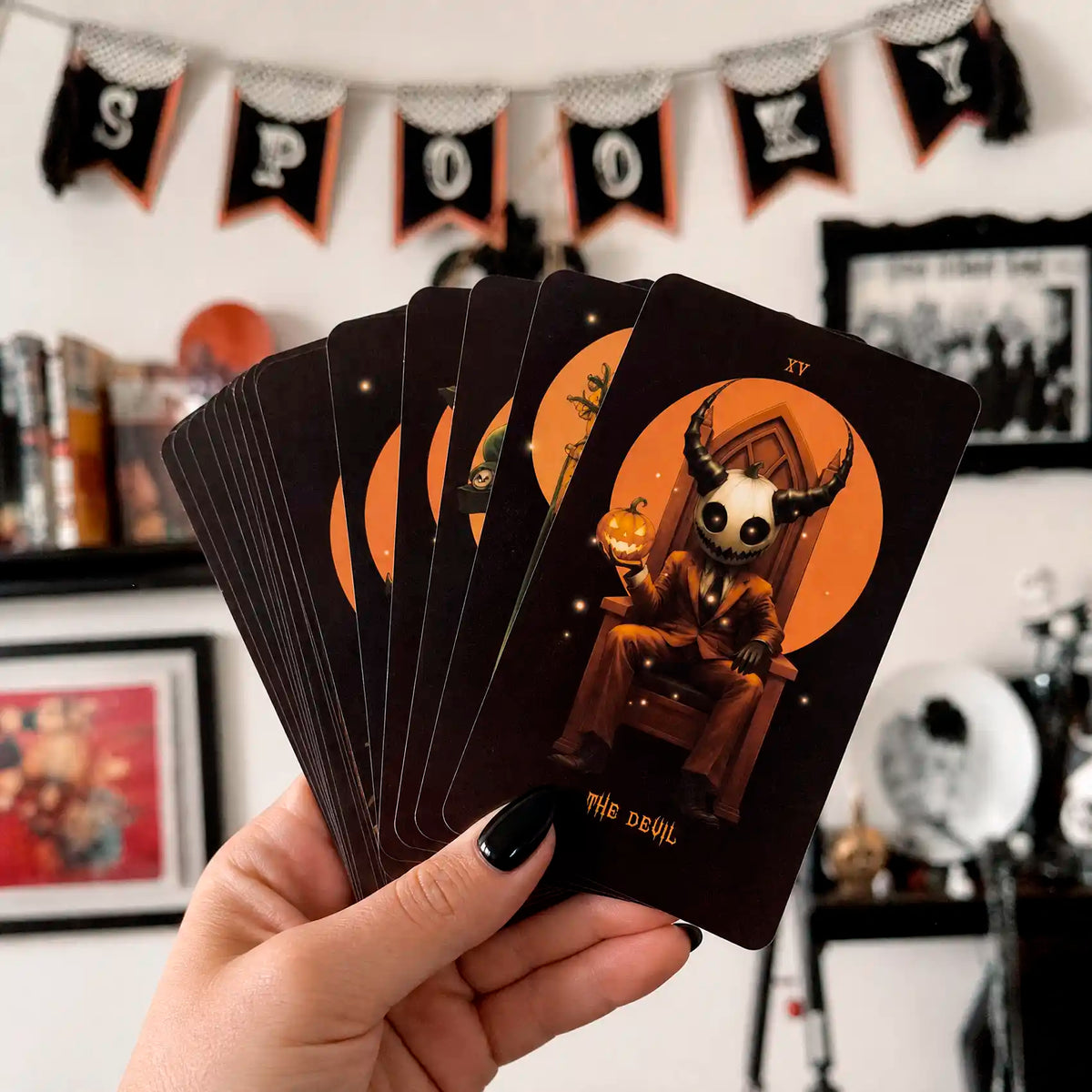 Halloween Tarot cards held in hand with black nail polish, showing The Devil card and orange black Halloween artwork
