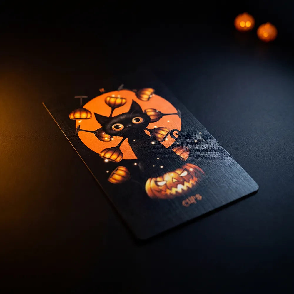 Close-up of Halloween Tarot Cups card with black cat and glowing pumpkin elements on dark background