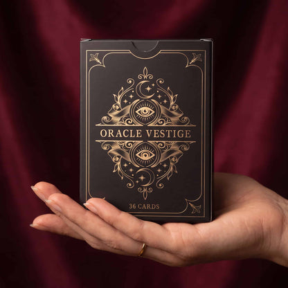 Hand holding Oracle Vestige box, 36-card Lenormand-style oracle deck in black and gold