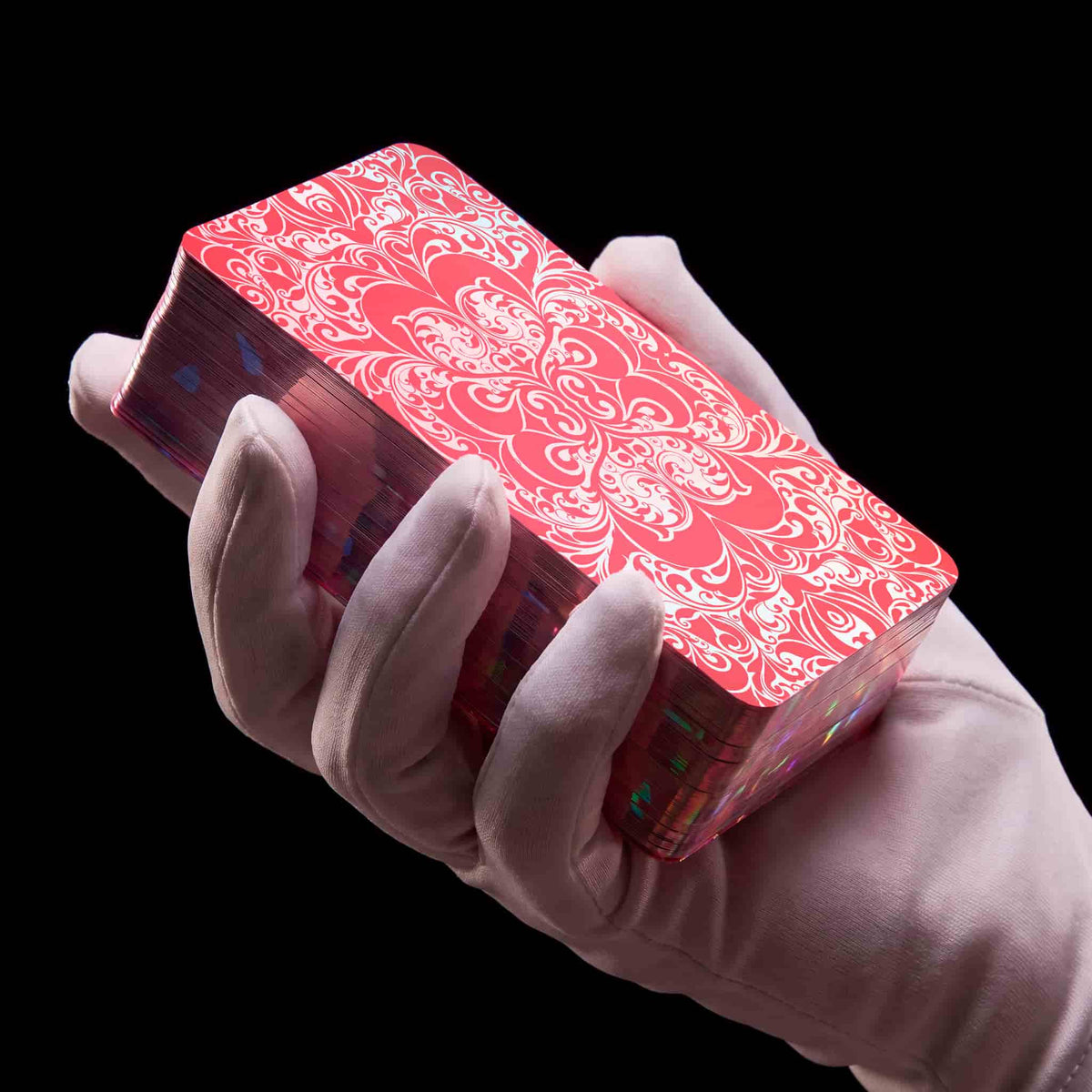 Gloved hand holding La Petite Flamme Tarot deck, red ornate card back with holographic gilded edges
