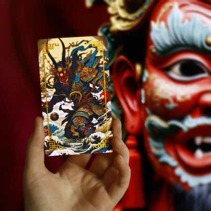 Hand holding Journey to the West Tarot The Devil card in front of a red Chinese opera mask