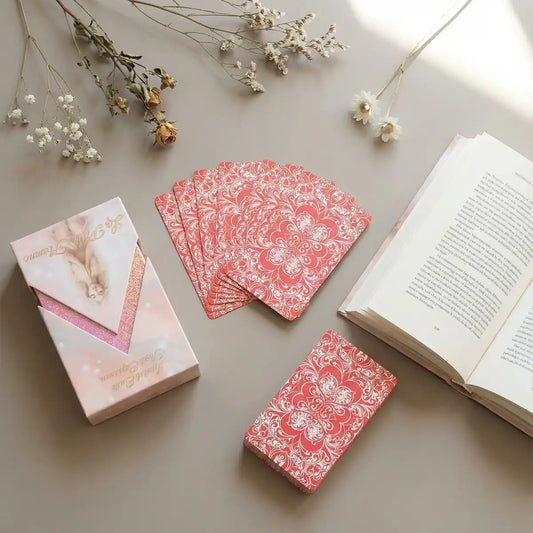 La Petite Flamme tarot deck with ornate pink card backs, collector box and guidebook in a soft romantic flat lay