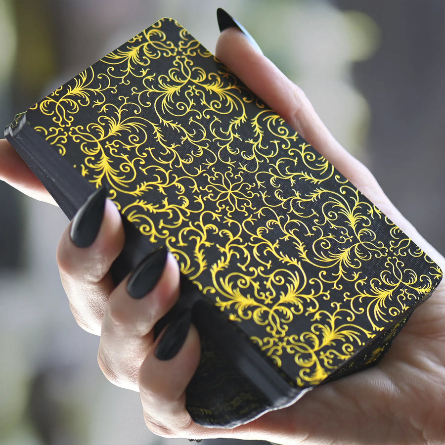 Hand holding Les Fantaisie d'Amour Tarot deck, black card backs with gold metallic foil filigree