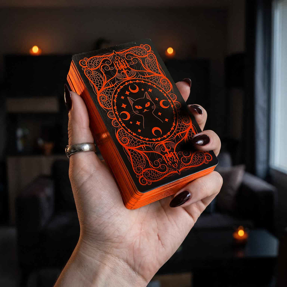 Hand holding Halloween Tarot deck, black and orange cat card back with orange gilded edges
