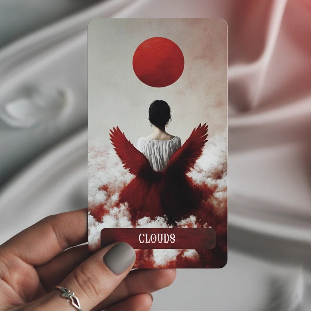 Occult Lenormand Clouds card with woman and red wings held in hand against soft fabric background