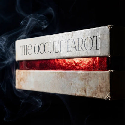 Occult tarot deck box with red gilded edges and dark smoky background close up
