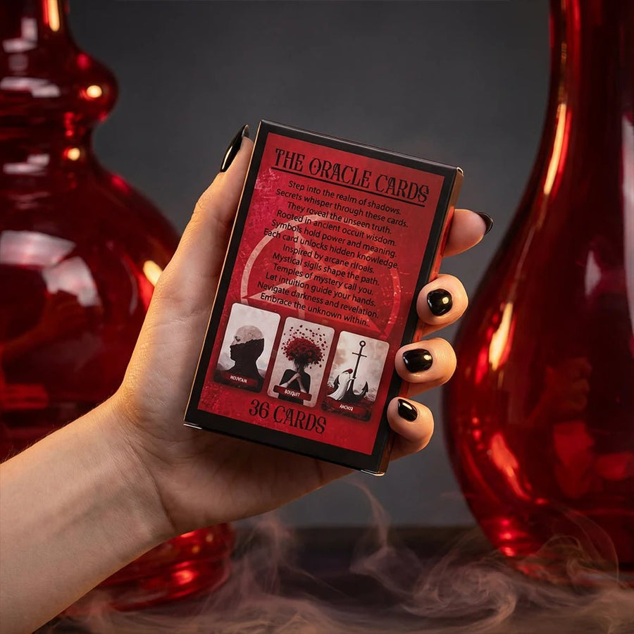 Back of oracle cards box with red occult design and description text held in hand with dark aesthetic background and smoke