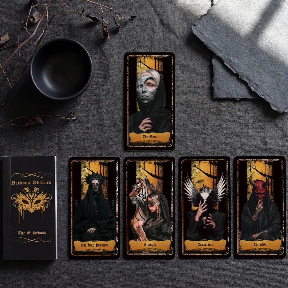 Persona Obscura Tarot cards lineup with cup and guidebook, black-and-gold Rider–Waite style deck