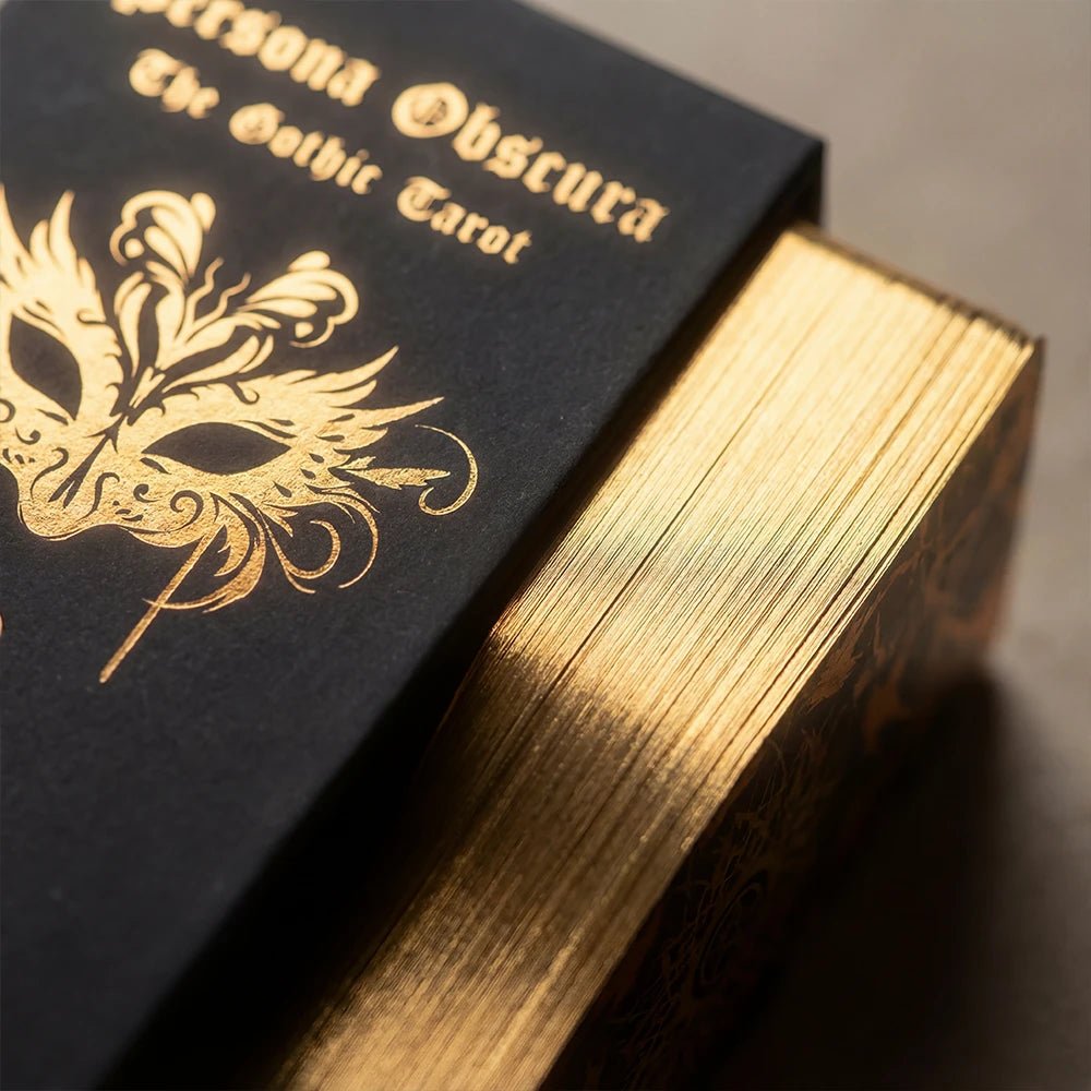 Macro close-up of Persona Obscura Tarot gold gilded edges and black box with gold foil logo