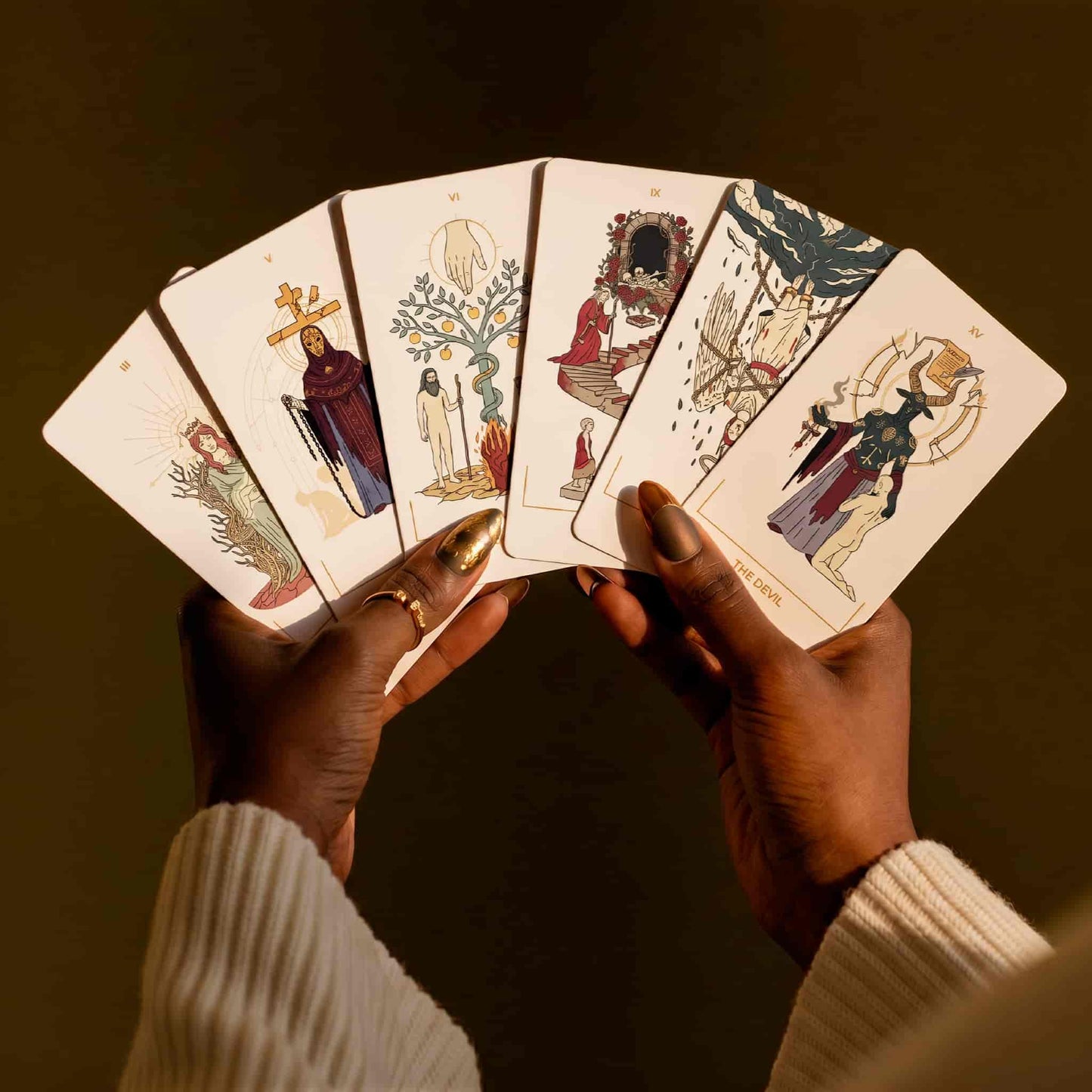 Hands holding five Seraphim Tarot Major Arcana cards inspired by Biblical angels and Revelation imagery.