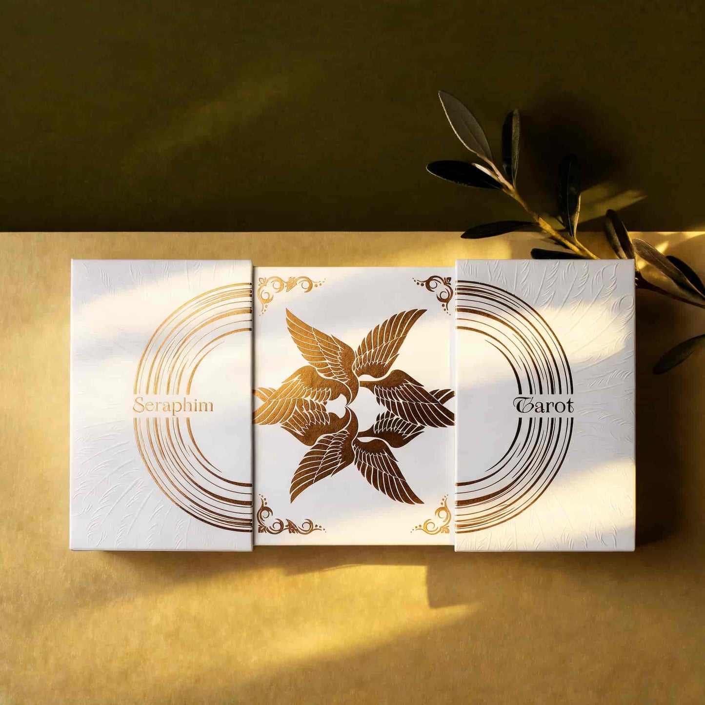 Overhead view of the Seraphim Tarot box-in-box packaging opened around the central gold foil angel design.