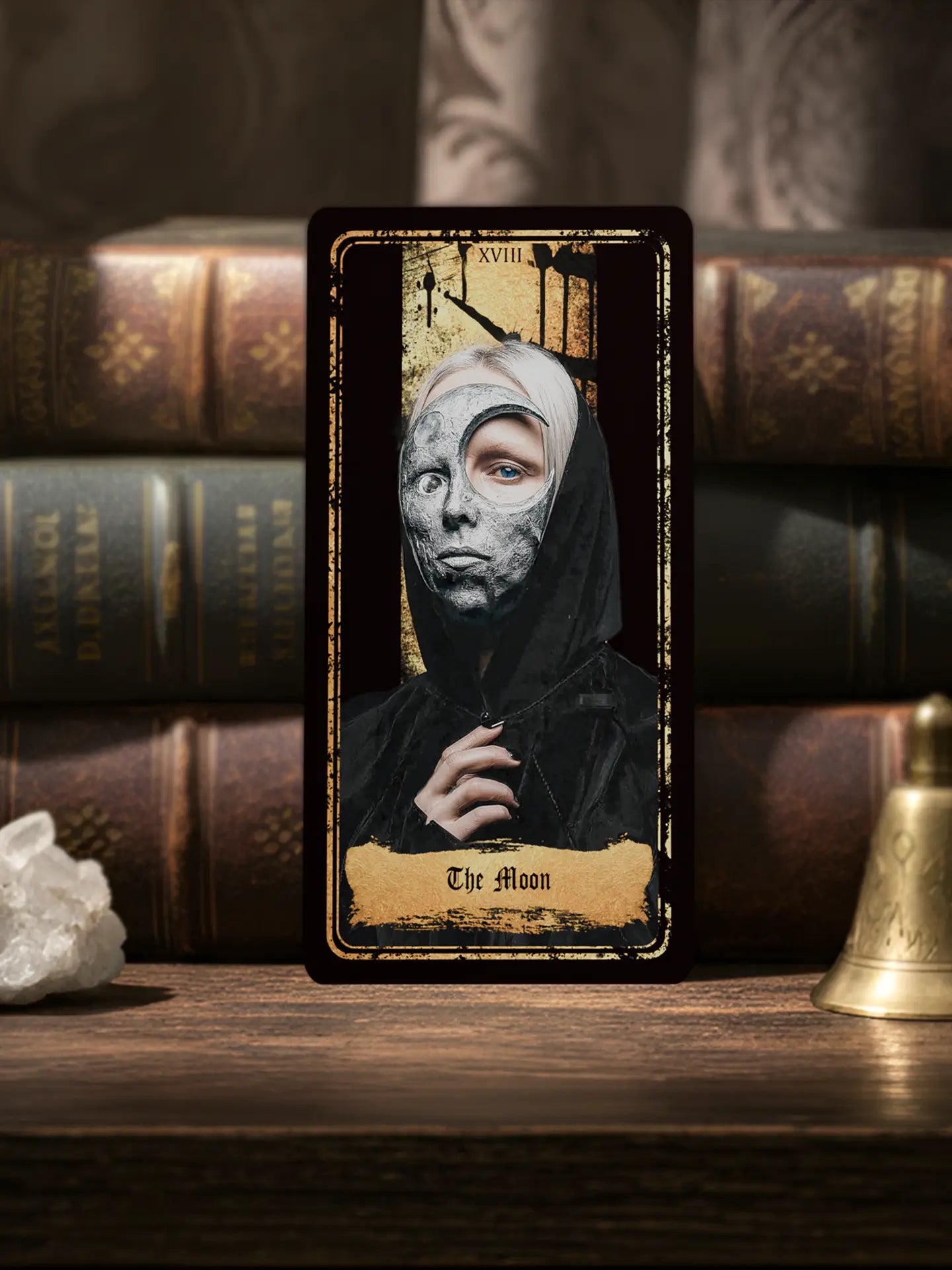 Tarot card titled 'The Moon' with a hooded figure against a dark background, surrounded by books and a crystal, 70x140mm matte finish 400gsm paper 