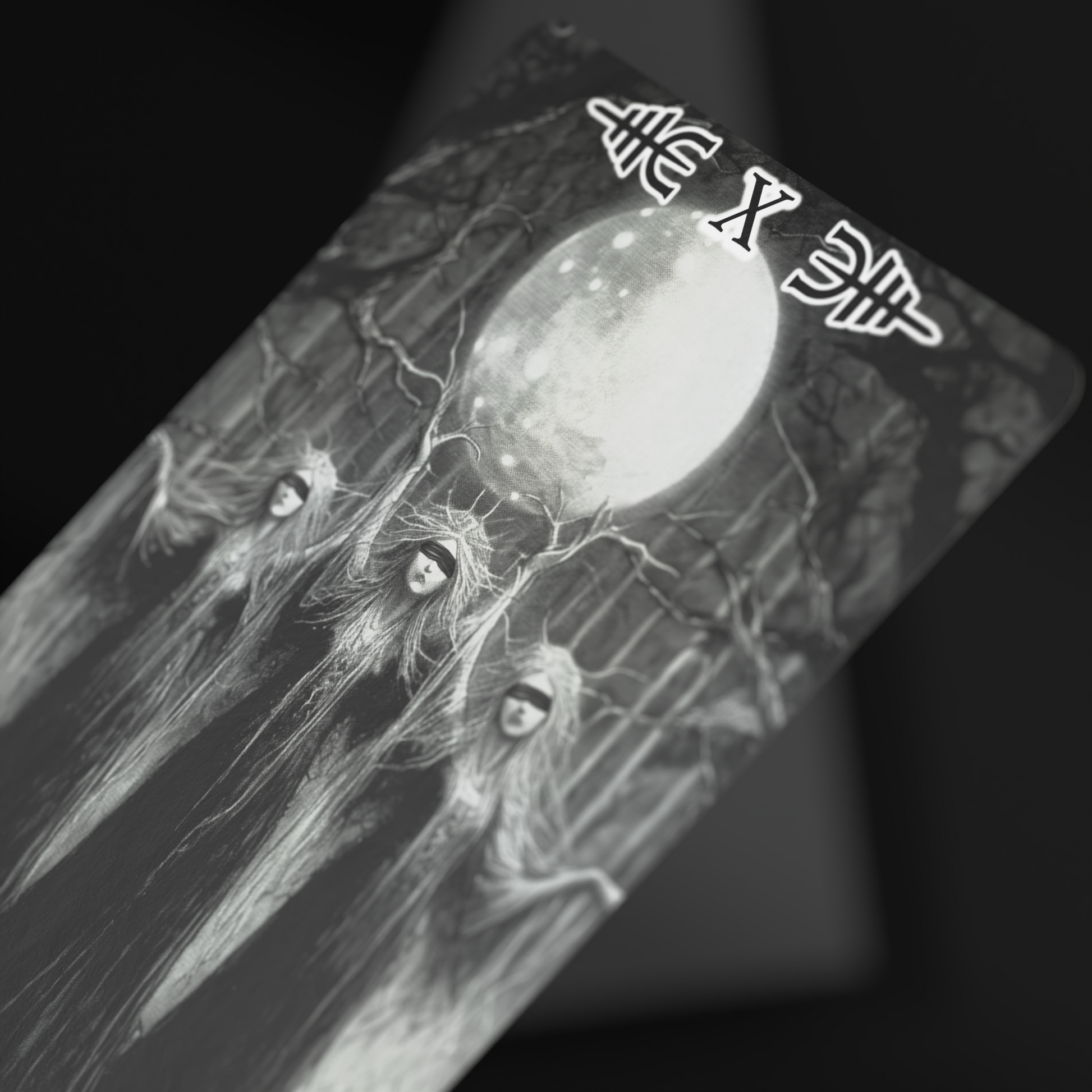 Close-up of Viking tarot card featuring three mysterious hooded women under a full moon, black and white fantasy tarot deck illustration, gothic oracle deck art for collectors and divination enthusiasts