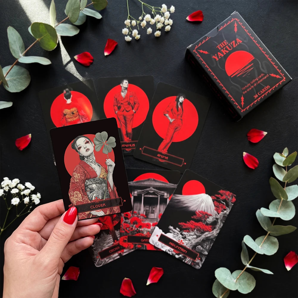 Yakuza Lenormand cards flat lay with red and black design, hand holding clover card, surrounded by petals and greenery