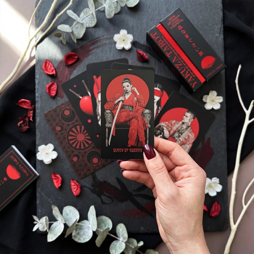 Flat-lay Yakuza Tarot with box and cards on dark table, crimson accents and petals